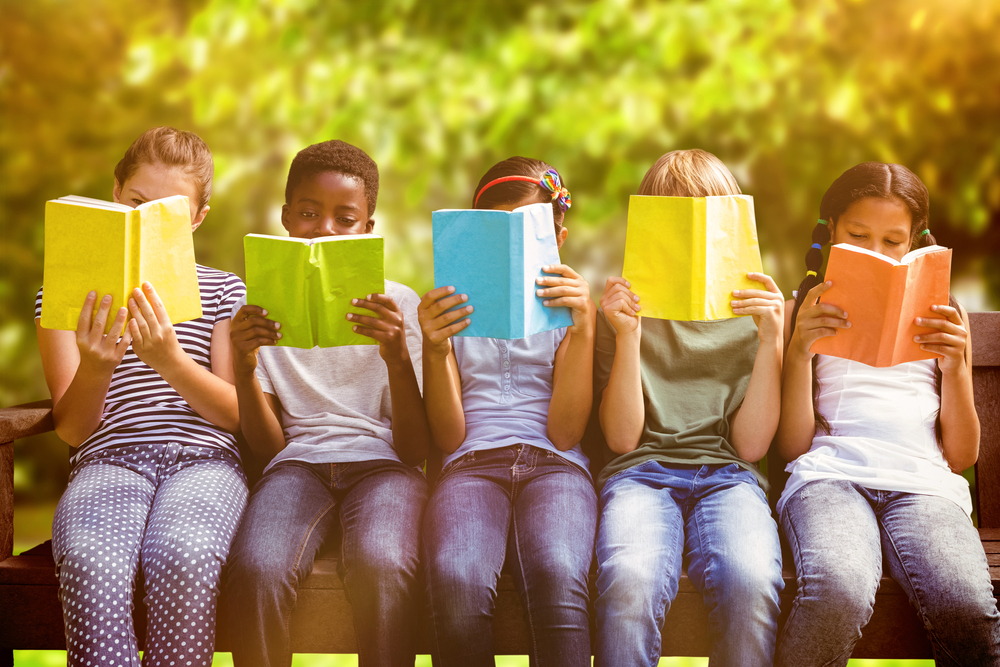 niños en un parque leyendo libros del genero literario comedia y poesía