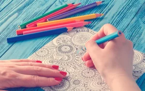 Alguien que tiene como hábito dibujar mandalas utilizando lapices de colores y papel para sacar toda su cratividad
