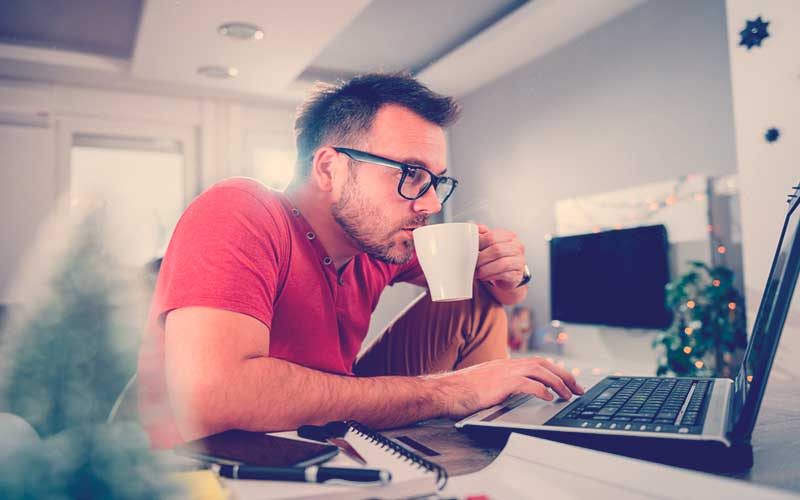 hombre joven haciendo teletrabajo en la sala de casa