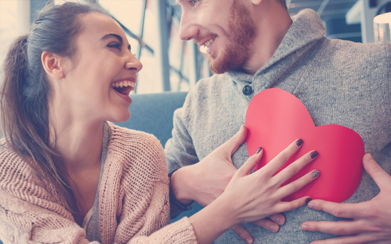 pareja sonríe dando un corazón en plan romántico