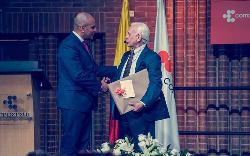 uno de los momentos más emotivos de la conferencia, el director de Compensar, Carlos Mauricio Vásquez, le entrega un detalle al doctor Rodolfo Llinás, 