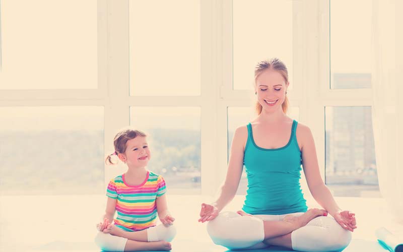 Mamá haciendo yoga con su hija. 