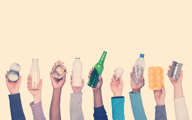 Personas levantando la mano con productos de reciclaje