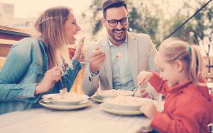 Familia sentados en la mesa comiendo juntos