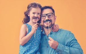 Niña con su papá poniéndose un bigote en su cara