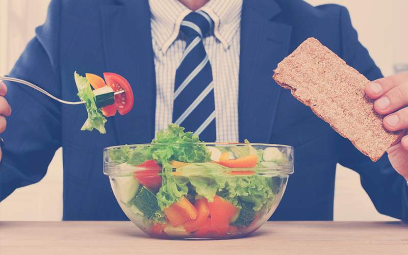 Hombre en traje comiendo verduras 