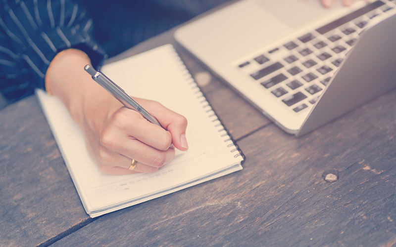 cerrar el contenido de escritura a mano de una mujer de negocios o algo en un ordenador portátil con el uso de una laptop en una mesa de madera fuera de casa, concepto de estilo de vida