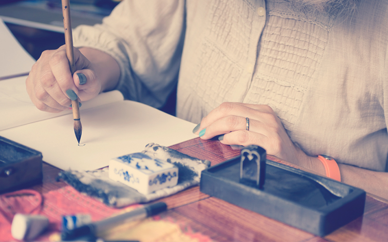 Mujer pintando en una hoja el arte Sumi-e