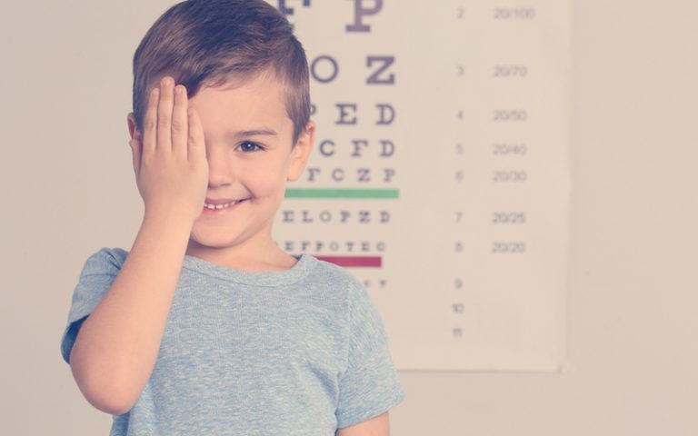 Niño cubriéndose un ojo mientras sonríe para la foto