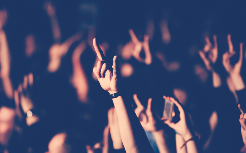 Persona mostrando el signo de los cuernos durante un concierto de banda de rock en el club. Una multitud en un concierto. Dos dedos de mano roca.