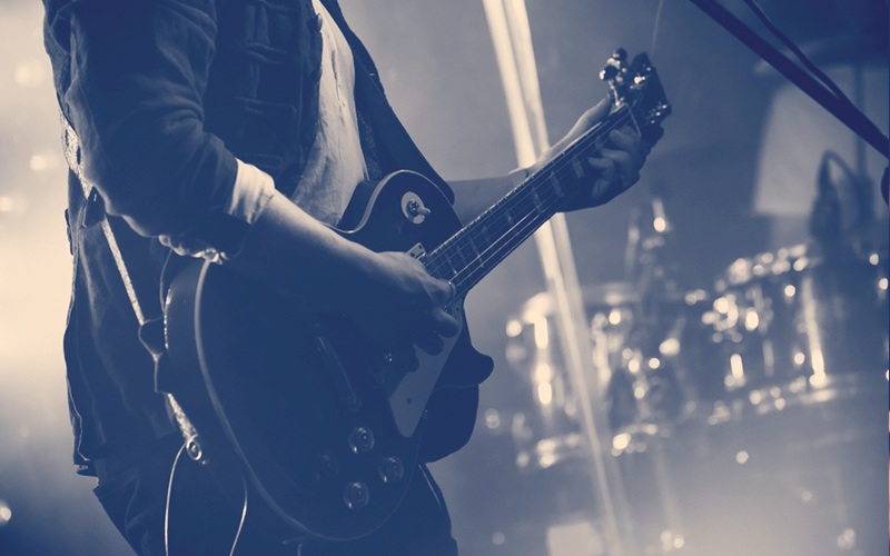 silueta de guitarra en acción en el escenario frente a la multitud de conciertos