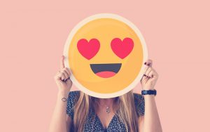 Mujer sosteniendo un emoji corazón ojos cara