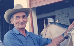 Campesino colombiano junto a un caballo blanco