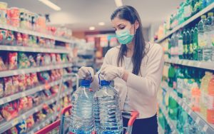 Compradora colombiana haciendo compras en el supermecado con tapabocas y guantes