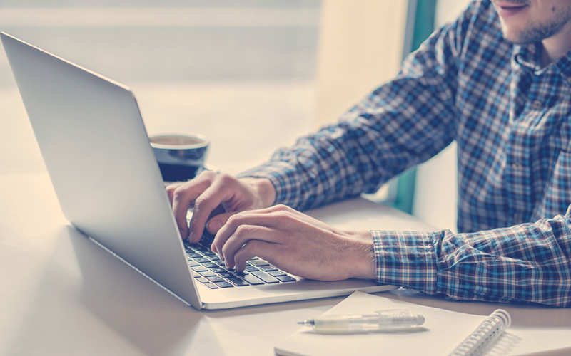 Hombre escribe en su computador portátil