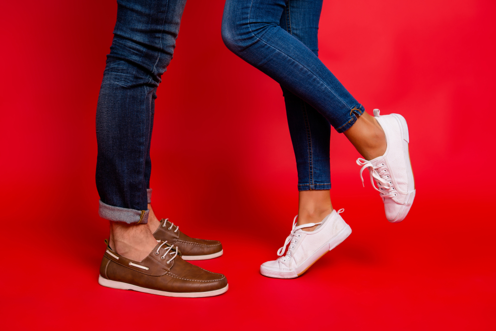 Hombre con zapatos de cuero y una mujer con tenis blancos. 