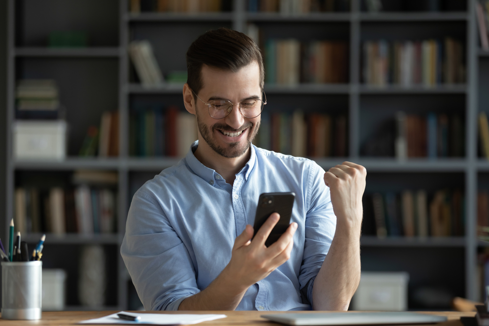 Emprendedor mirando su celular y celebrando 