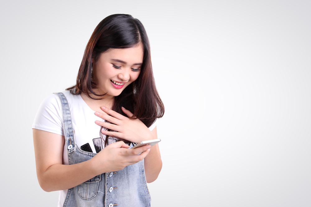 Mujer con una cara alegre mirando su celular