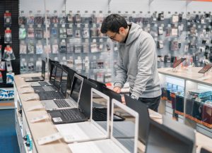 Hombre en una tienda de tecnología decidiendo qué computador comprar