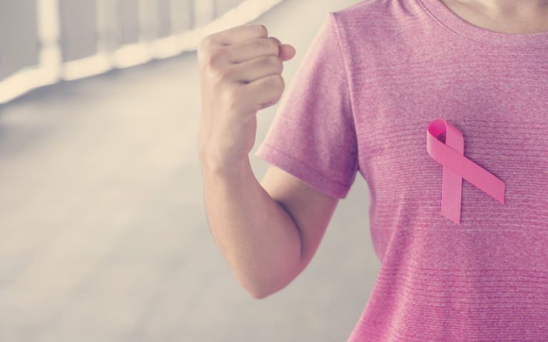 Mujer con camisa que tiene un lazo rosa representando la lucha contra el cáncer de mama