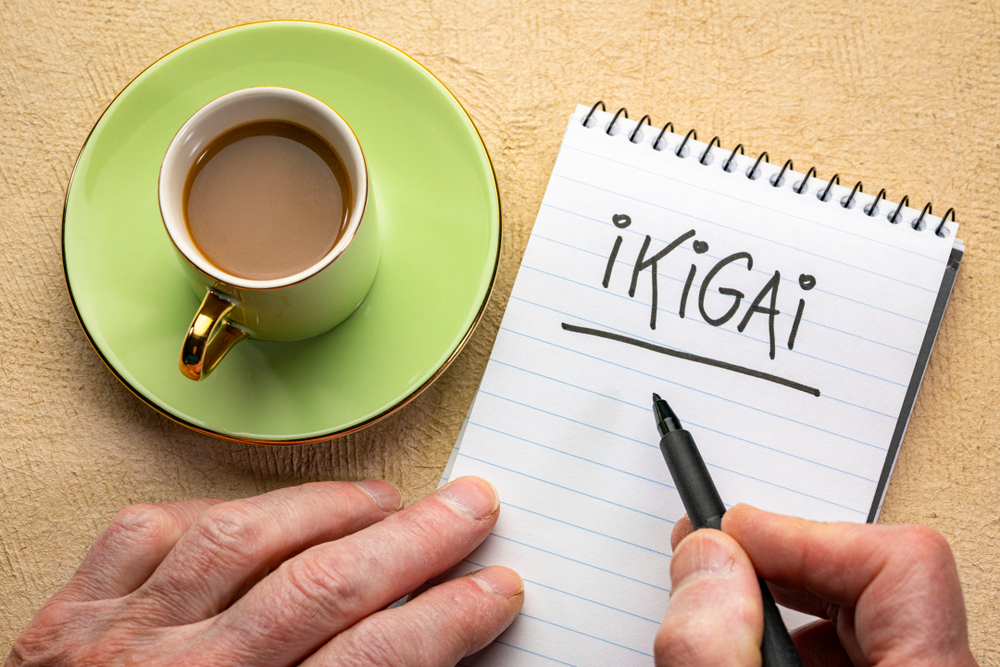 Mano de un hombre con una libreta donde escribe Ikigai