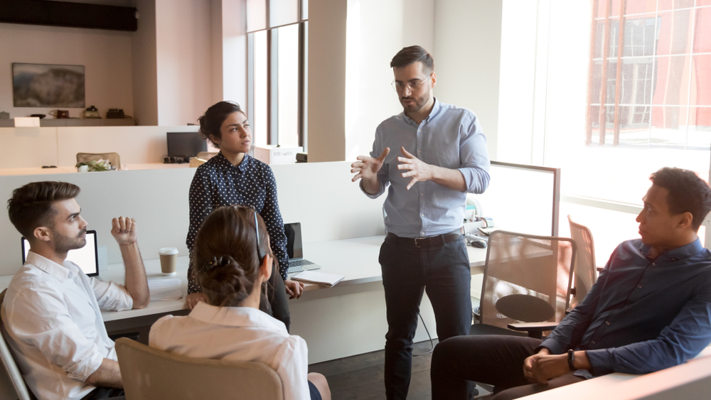 jefe manteniendo la distancia y hablándole a su equipo de trabajo