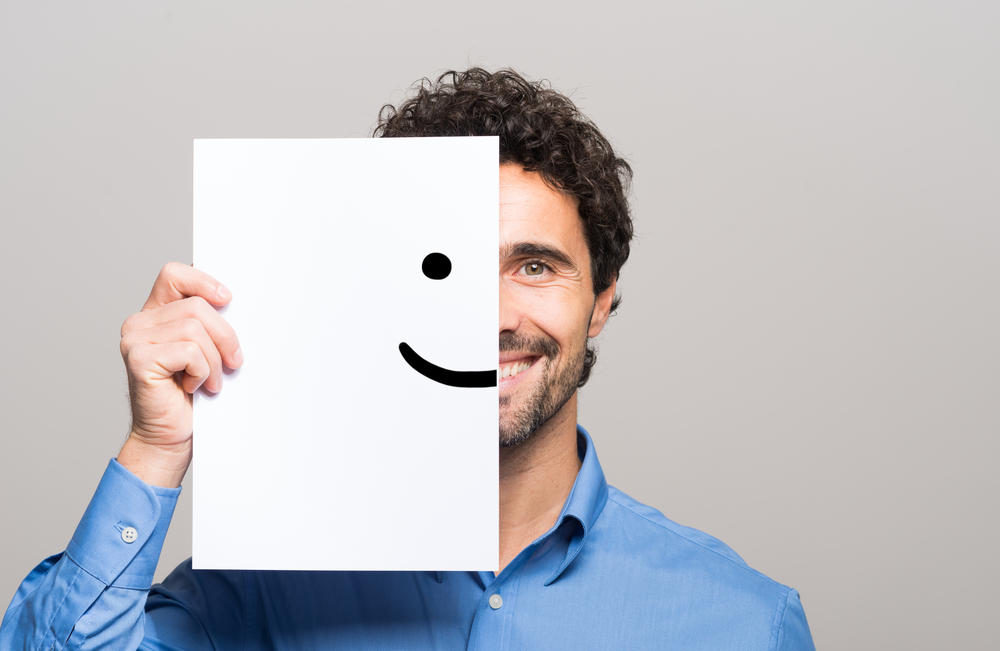 Hombre feliz cubriendo la mitad de su cara con un emoticón sonriente