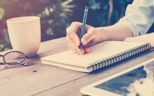 Persona escribiendo con lápiz en un cuaderno