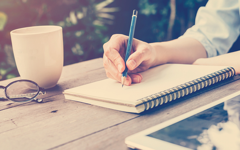 Persona escribiendo con lápiz en un cuaderno