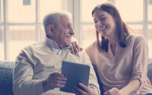 Abuelo junto a su nieta riéndose viendo una tablet