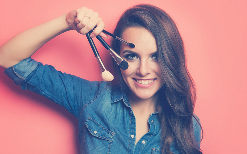 Retrato de mujer con cepillos de maquillaje cerca de la cara