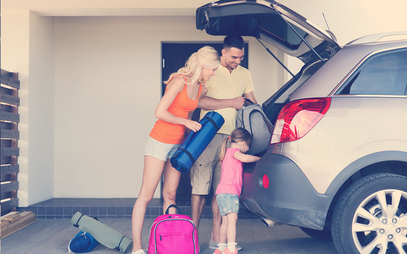 familia empacando cosas en el auto estacionado en casa