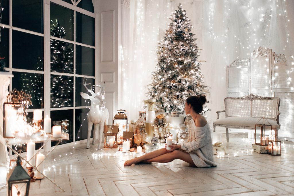 Mujer con suéter blanco, cálida y acogedora noche en el diseño interior de Navidad.