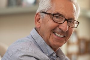 Persona mayor con gafas sonriendo ante la cámara