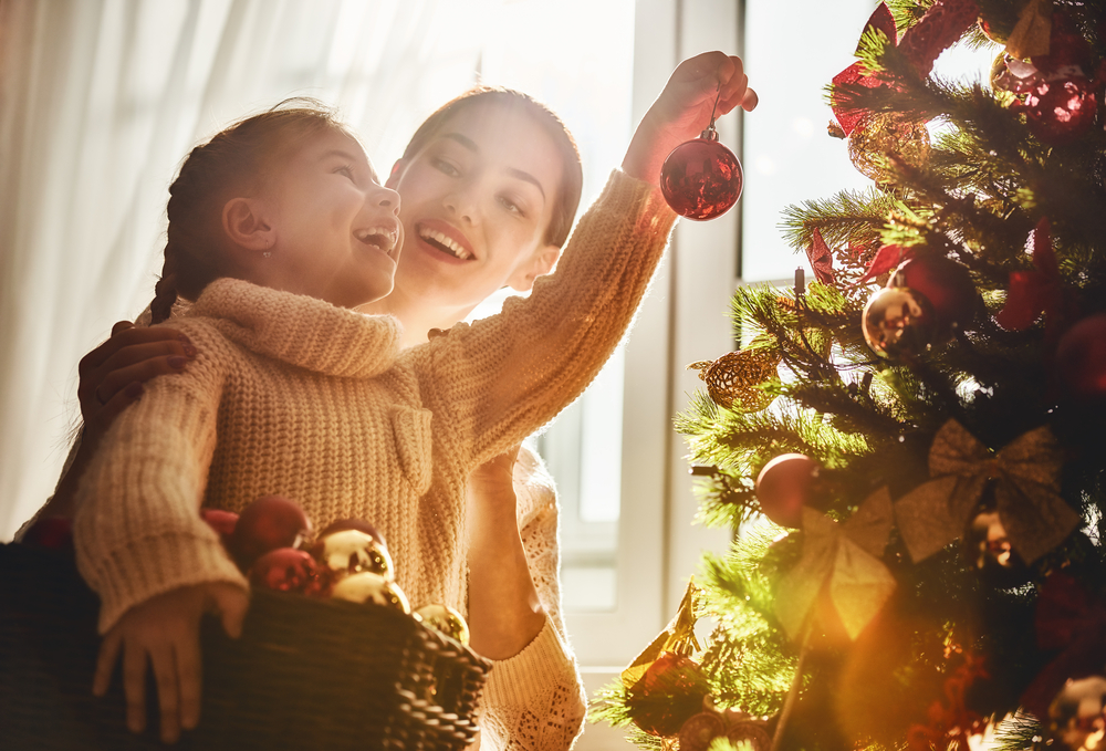 Mamá e hija decoran el árbol de Navidad en el interior