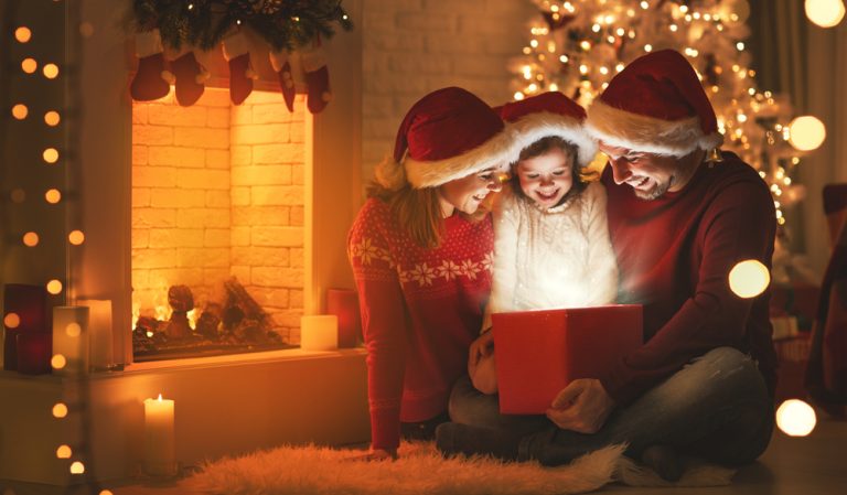 Familia compartiendo en Navidad y abriendo un regalo para su hija