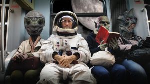 En una nave espacial, un astronauta, sentado junto a monstruos extraterrestres,
