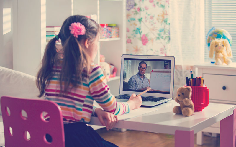 Niña estudiando y prestando atención a clase virtual