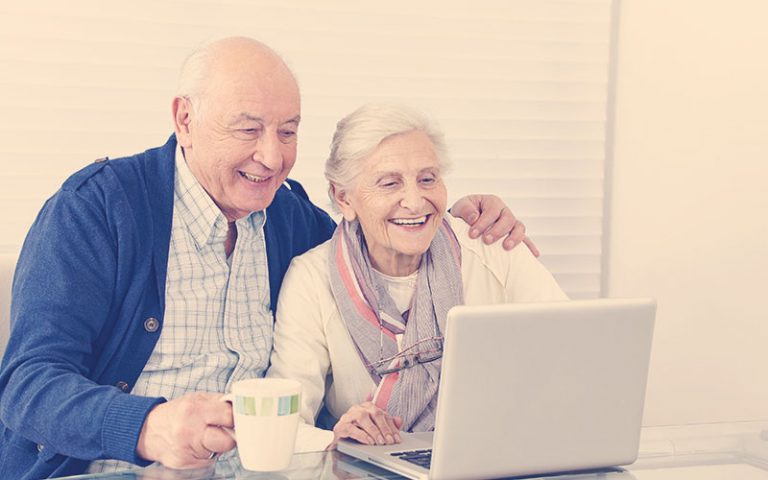 abuelos teniendo sonriendo frente a un computador
