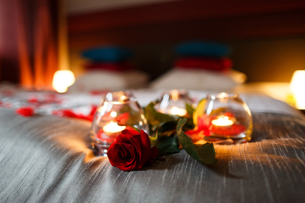 Noche romántica. Rosa y velas en la cama.