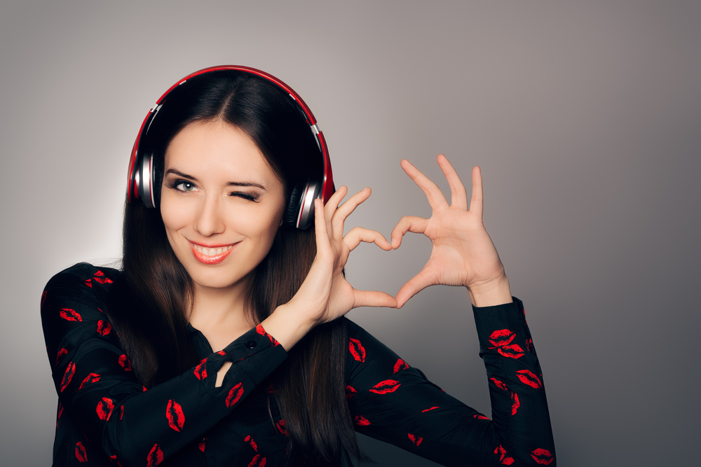 Mujer escuchando música y haciendo con sus manos un símbolo de corazón
