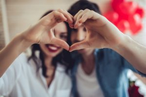 Hermosa pareja joven en casa está haciendo señas de corazón con las manos