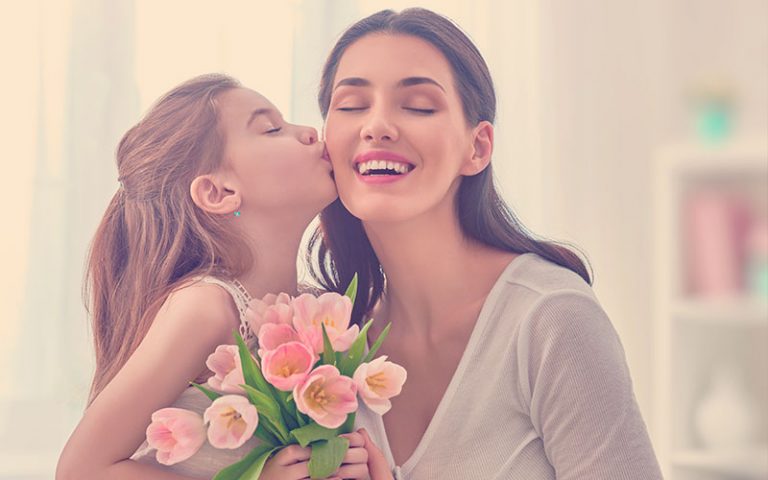 Mamá junto a su hija quien le entrega unas rosas