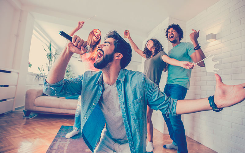 Grupo de amigos jugando karaoke en casa. 