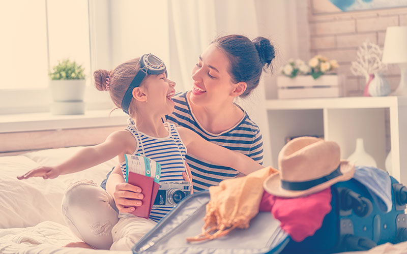 Feliz familia preparándose para el viaje. Mamá e hija están empacando maletas para el viaje.