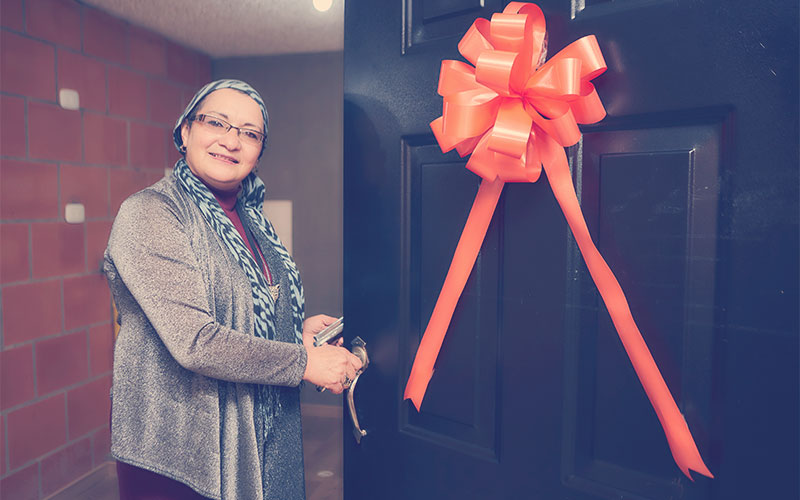 Señora feliz abriendo la puerta de su nuevo apartamento Reserva de San David, proyecto VIS ubicado en La Esperanza Sur