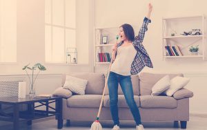 mujer feliz limpiando la casa al mismo tiempo que canta