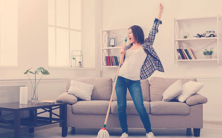 mujer feliz limpiando la casa al mismo tiempo que canta
