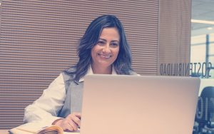 Colaboradora sonriendo frente a un computador mientras toma un curso de habilidades profesionales