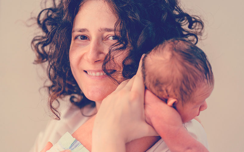 Mamá sonriendo mientras sostiene a su hijo